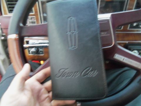 2000 Mercury Grand Marquis - Owner's manual for a Lincoln Town Car is held up in front of the vehicle's interior.
