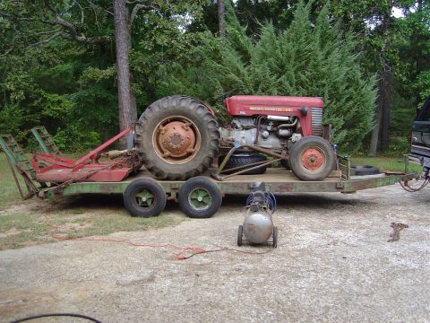 1986 Ford Bronco - A red Massey Ferguson tractor is loaded onto a trailer, accompanied by an air compressor and brush cutter.
