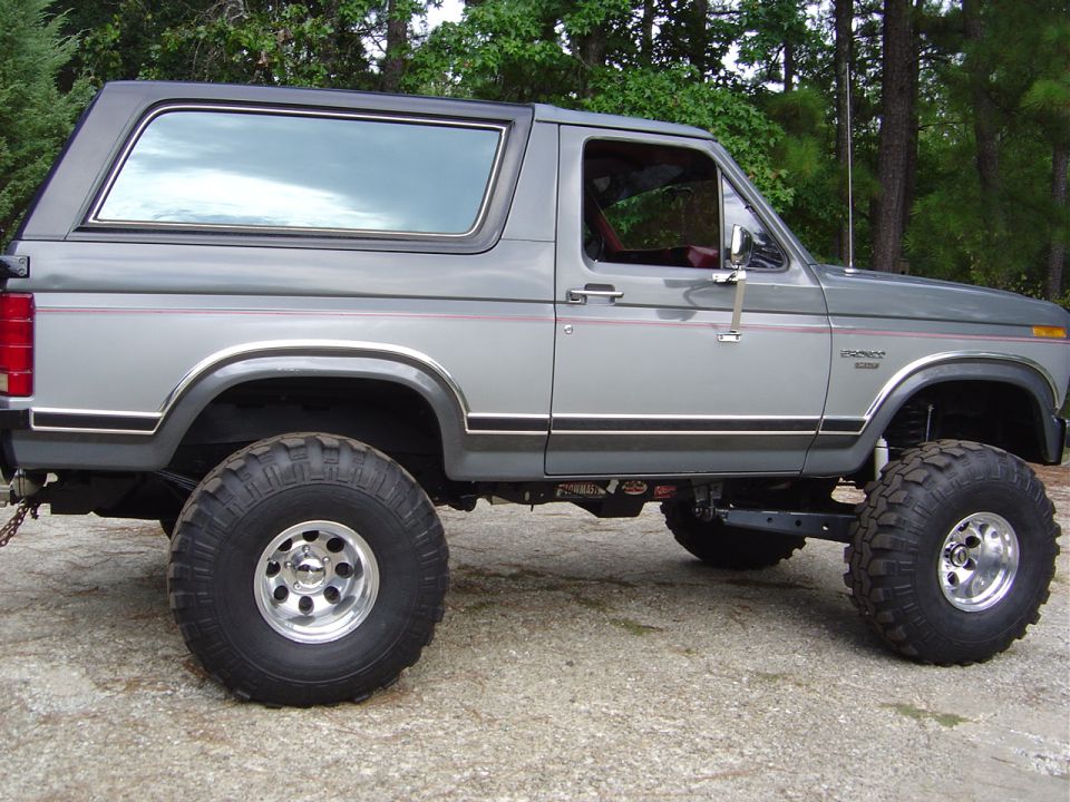Side view of a lifted gray 1986 Ford Bronco with large off-road tires