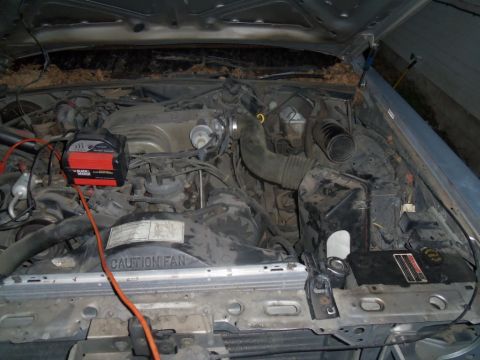 2000 Mercury Grand Marquis - Engine bay of a Ford Panther platform vehicle, likely from the 1990s, with a battery charger attached.