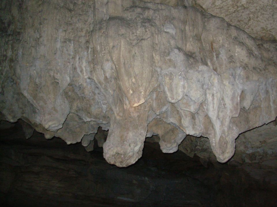 Cave interior with flowstone and stalactite rock formations on ceiling