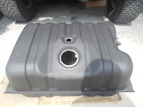1991 Ford Bronco - A black fuel tank is shown from above, with a vehicle's tire and undercarriage in the background.