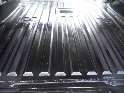1991 Ford Bronco - The ribbed metal floor of a vehicle interior is visible, with tie-down points and bright reflections.