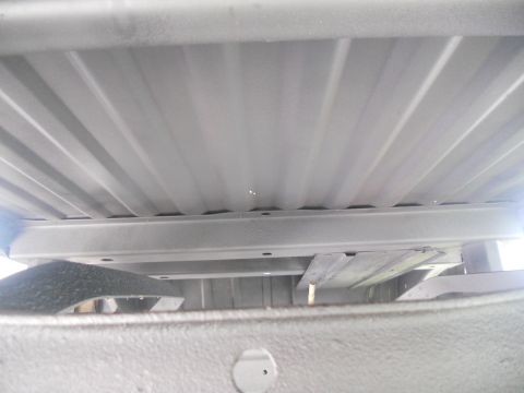 1991 Ford Bronco - The underside of a vehicle bed is shown, revealing structural beams and corrugated metal sheeting.