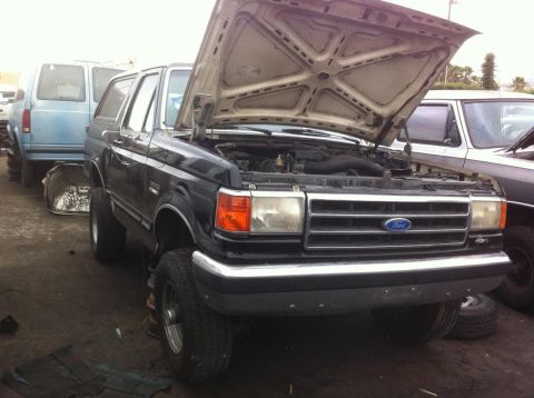 1992 Ford Bronco - This 1992 Ford Bronco is parked in a junkyard with its hood open.