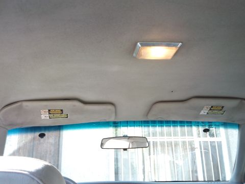 1998 Ford Crown Victoria - View of the interior ceiling, including the dome light and sun visors with air bag warnings.