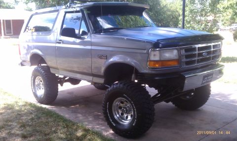 1994 Ford Bronco - This lifted 1994 Ford Bronco has large off-road tires and is parked on a driveway.