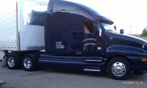 1994 Ford Bronco - A semi-truck with a trailer is parked on pavement. The truck has company information visible on its side.