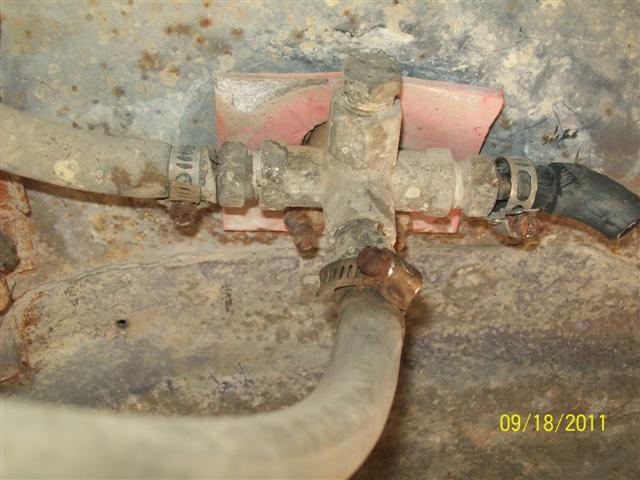 Close-up of a rusty fuel filter housing with hoses attached