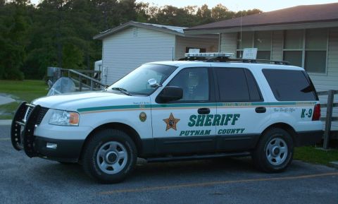 2006 Ford F-150 - A white sheriff's SUV, marked "PUTNAM COUNTY SHERIFF" and "K-9", is parked in front of a building.