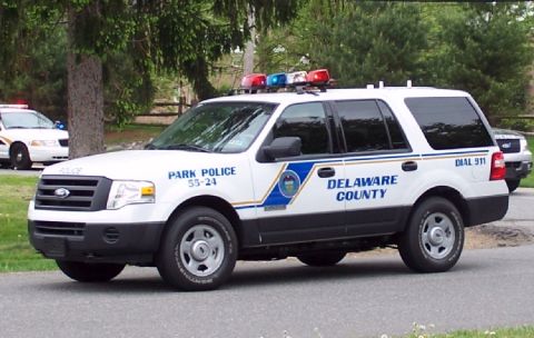2006 Ford F-150 - A white police SUV with emergency lights on top is parked on a street, with trees in the background.