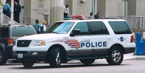 2006 Ford F-150 - A white police SUV is parked on the street in front of a building with people standing nearby.
