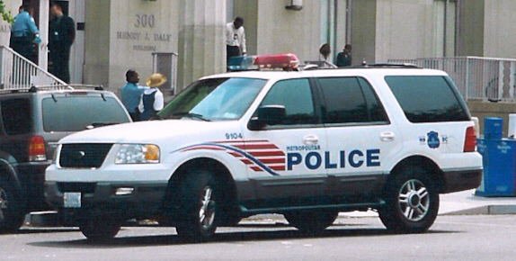 White police SUV, side view, with red and blue light bar. "Metropolitan Police" text on door