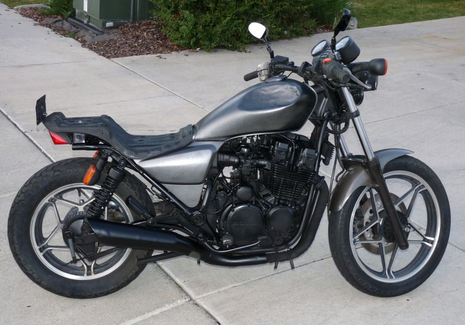 Side view of a customized motorcycle with a gray tank and black exhaust