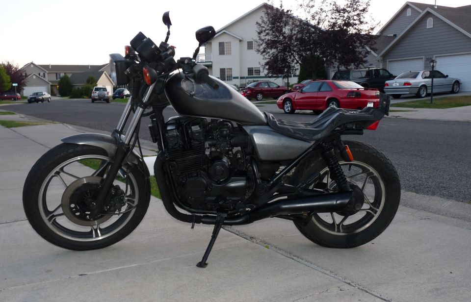 Gray motorcycle parked on sidewalk in front of houses