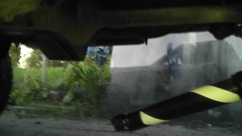 1989 Ford Bronco - The underside of a vehicle is visible, with a striped pole in the foreground.