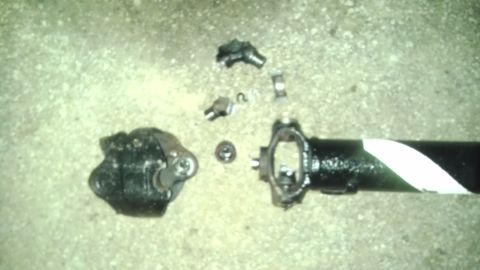 1989 Ford Bronco - Disassembled driveshaft components, including a U-joint and yoke, lie scattered on a concrete surface.