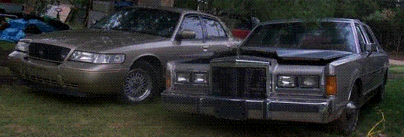Two sedans, one gold and one silver, parked on grass