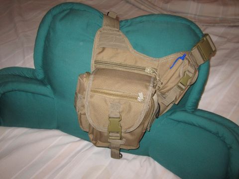 1990 Ford Bronco - A tan tactical sling bag with multiple pockets and zippers is displayed on a teal pillow.