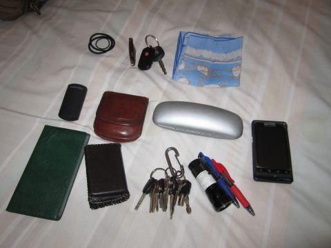 1990 Ford Bronco - A collection of personal items including keys, wallets, a phone, and a glasses case are spread out on a white, striped surface.