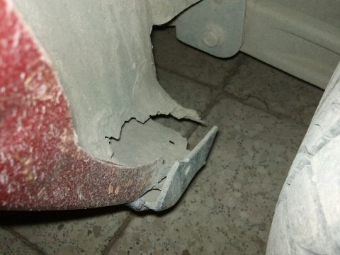 1998 Ford Crown Victoria - Close-up of a damaged and rusted red car fender edge, revealing structural compromise.