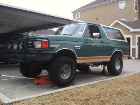 1989 Ford Bronco - 1989 Ford Bronco on jack stands, showing its lifted suspension and off-road tires.