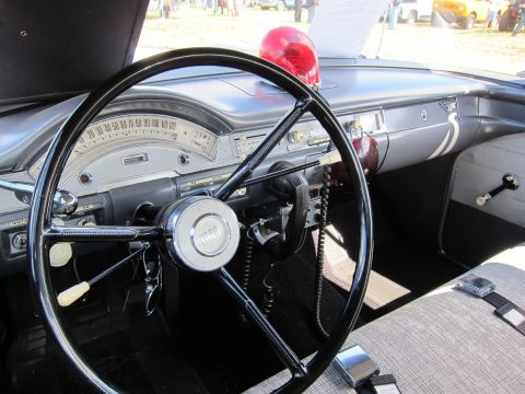 1991 Ford LTD Crown Victoria - black steering wheel, chrome dashboard and a red dome light of a 1950s-era car interior, photographed at an outdoor show.