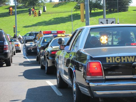 1991 Ford LTD Crown Victoria - black Ford LTD Crown Victoria marked Highway Patrol with an amber and red light bar waits in a line of cars.