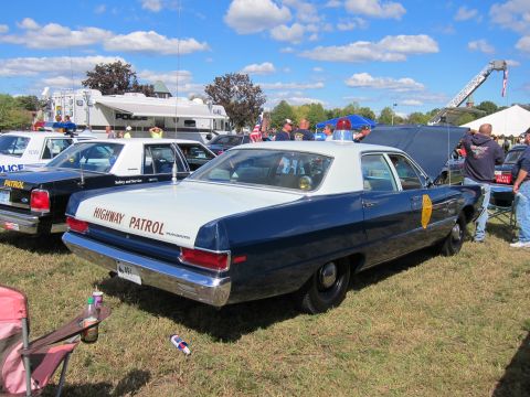 1991 Ford LTD Crown Victoria - Rear three-quarter view of a blue-and-white two-door Highway Patrol sedan parked on grass among other vintage police cars.