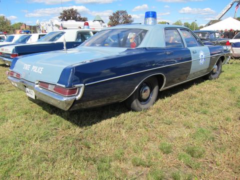 1991 Ford LTD Crown Victoria - vintage two-tone blue State Police full-size sedan with a blue rooftop beacon sits on grass at an outdoor police car show.
