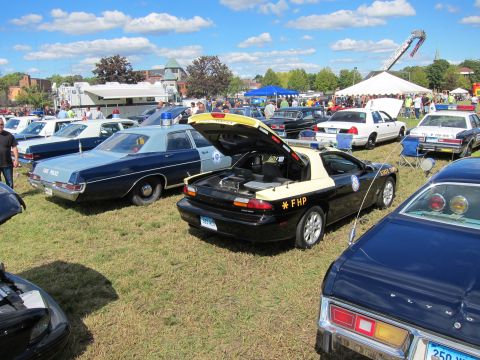 1991 Ford LTD Crown Victoria - black and tan FHP-marked sports coupe with its hood open sits among rows of police cars at a crowded outdoor show.