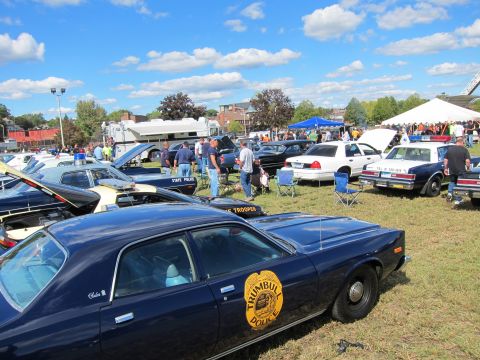 1991 Ford LTD Crown Victoria - dark blue Trumbull Police sedan with a gold circular door emblem sits among rows of classic police cars under a blue sky.