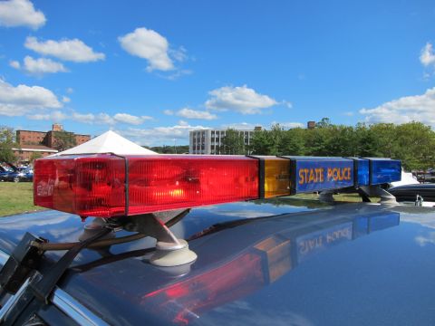 1991 Ford LTD Crown Victoria - close-up of a State Police roof light bar shows red, amber and blue lenses reflected on the car roof under a blue sky.