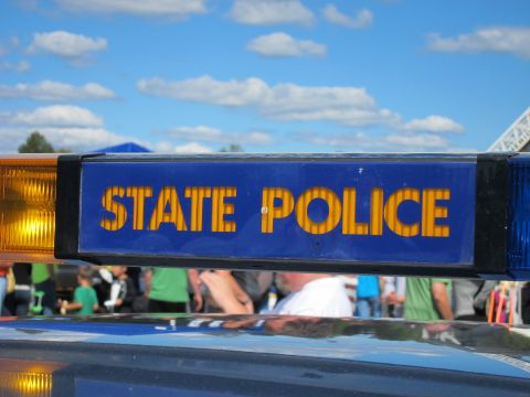 1991 Ford LTD Crown Victoria - vivid close-up of a STATE POLICE light bar panel in bright blue with gold lettering, with spectators visible behind it.