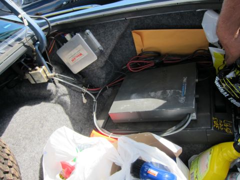 1991 Ford LTD Crown Victoria - Trunk corner showing a white Whelen control box and a black electronic unit connected by red and black wiring, beside plastic bags.