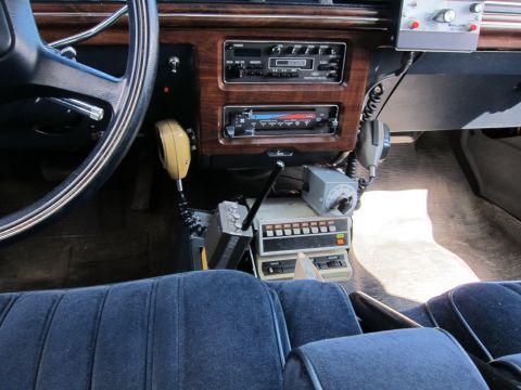 1991 Ford LTD Crown Victoria - Interior of a vintage car showing a woodgrain dash, cassette and AM/FM radios, a steering wheel, blue cloth seats, and a mounted two-way ra…