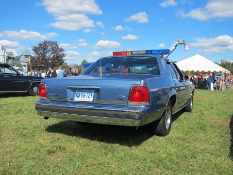 1991 Ford LTD Crown Victoria - Rear view of a blue Ford LTD Crown Victoria police sedan with a State Police roof lightbar and Connecticut plate, parked on a grassy show f…