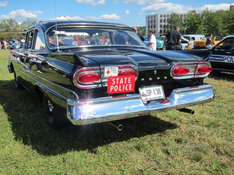 1991 Ford LTD Crown Victoria - Rear of a black classic Ford four-door sedan with round taillights, dual exhaust, and a red State Police plate over a Massachusetts plate S…