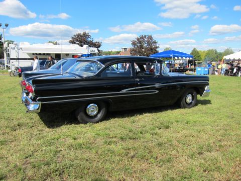 1991 Ford LTD Crown Victoria - Side profile of a black classic Ford two-door sedan with chrome side spear trim and whitewall-less tires, displayed on a grassy show field.