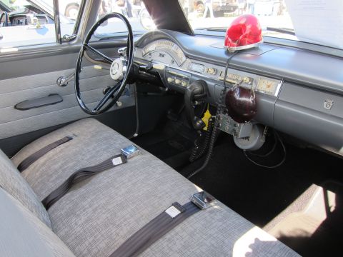 1991 Ford LTD Crown Victoria - Interior of a vintage sedan showing a black steering wheel, gray bench seat, column shifter, and a red dome light on the dash.