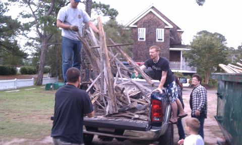 1979 Ford Bronco - Several people are working together to load scrap wood into the back of a pickup truck.