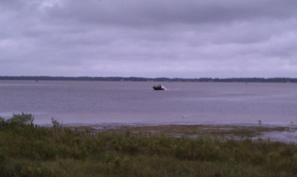 boat moving on a wide body of water under a cloudy sky