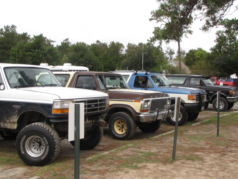 Brown and yellow 1979 Ford Bronco parked in a line with other trucks