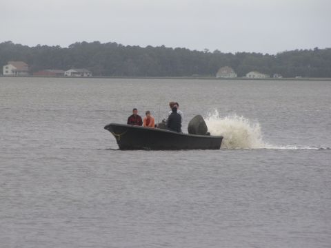 1979 Ford Bronco - A boat carrying three individuals speeds across the water, leaving a significant wake behind it.