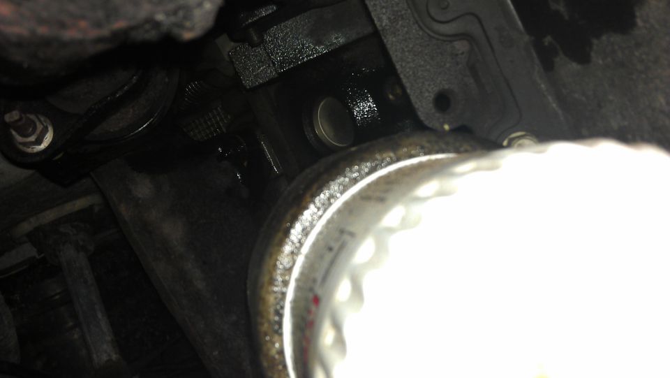 Close-up of greasy engine components and a metal pipe