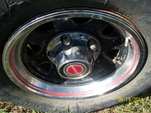 1979 Ford F-150 - A close-up view of a truck wheel, showing the tire, rim, and hubcap with a red accent stripe.