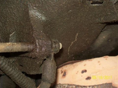 1979 Ford F-150 - Close-up view of oily mechanical parts and exhaust system on a vehicle's undercarriage.