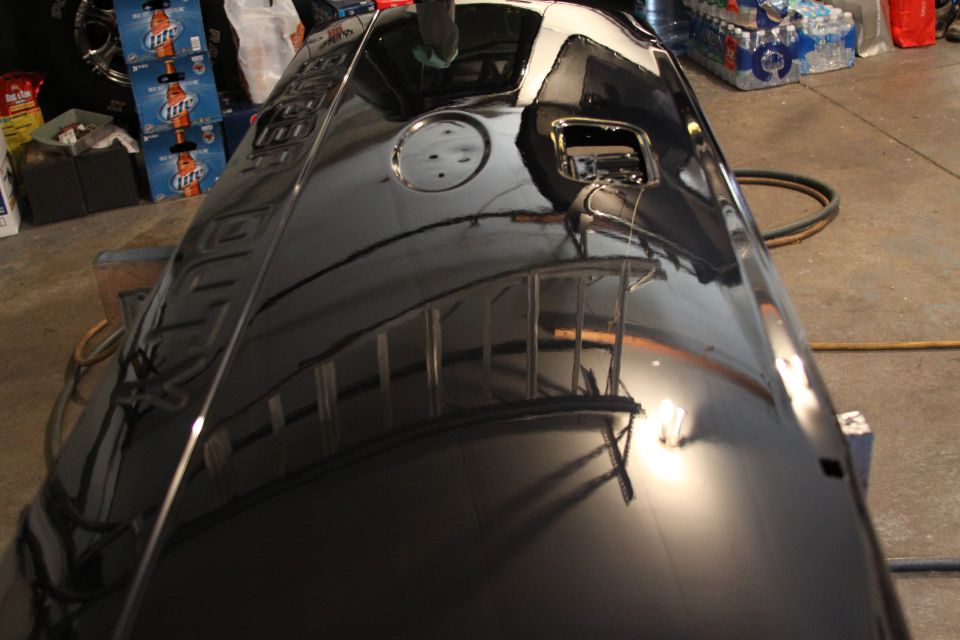 black pickup truck tailgate with a circular cutout and a rectangular cutout, reflecting a ladder and lights