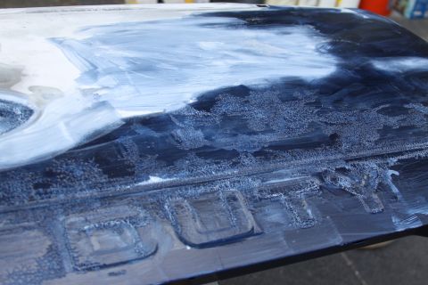 2006 Ford F-350 - Embossed text is visible on a dark vehicle part being worked on with white paste.