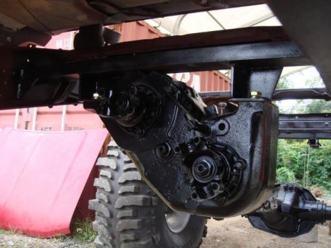 1982 Ford F-100 - The transfer case and drivetrain of a vehicle are shown, with a red hood in the background.